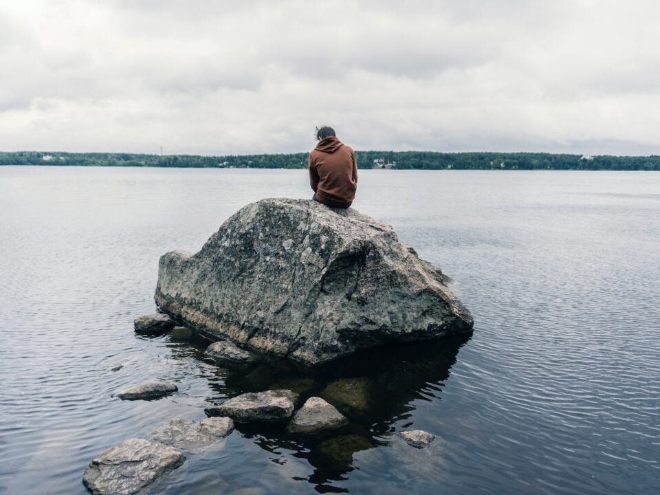 person sitting on rock surrounded by water