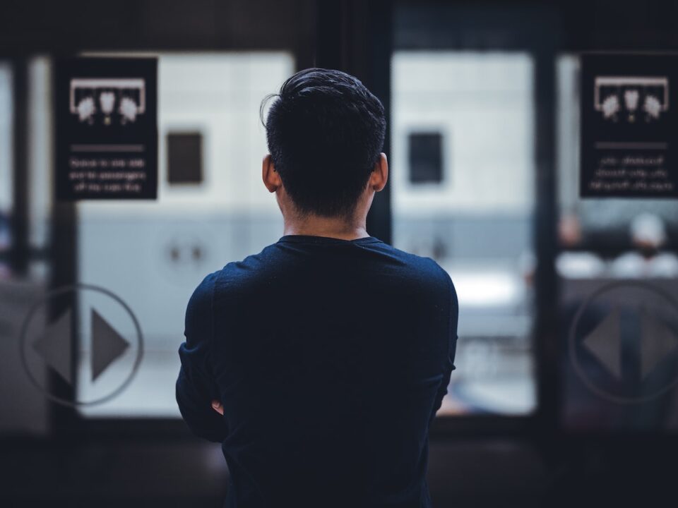 man wearing blue top facing glass door