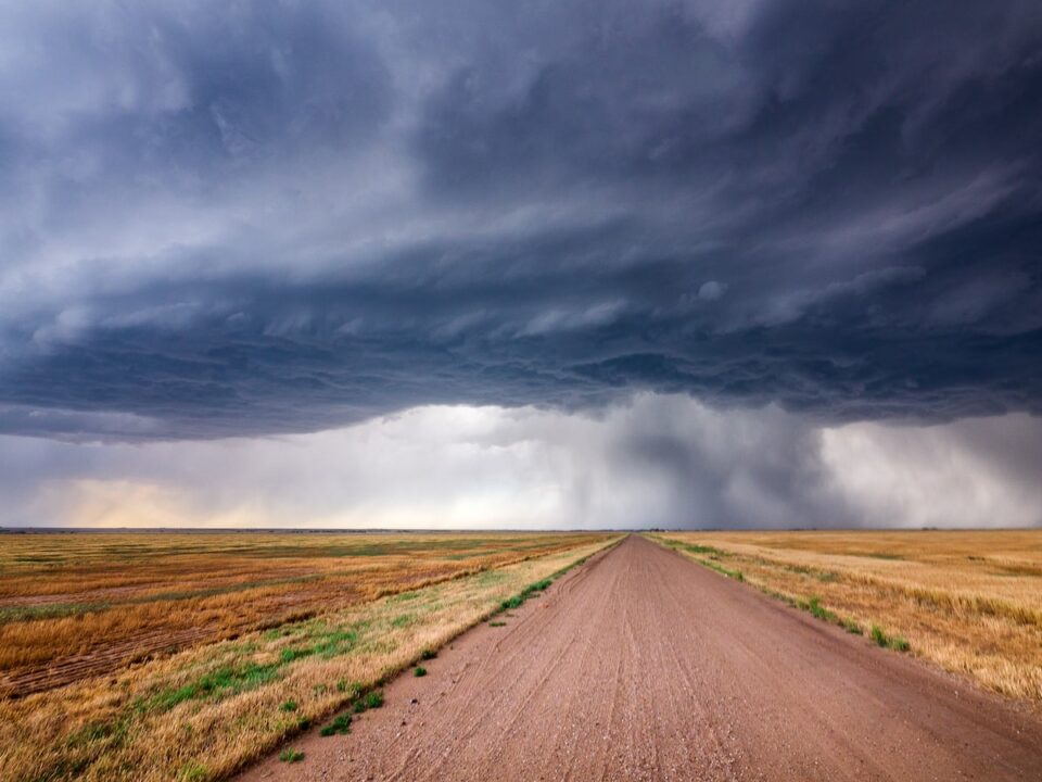 brown dirt road under gray clouds