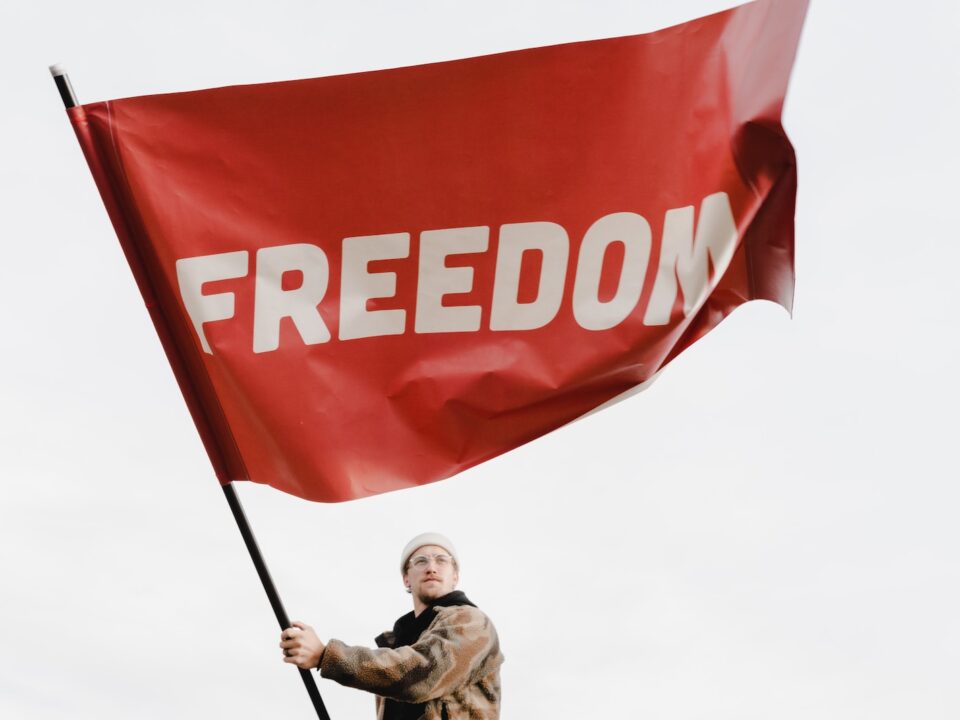 a man holding a red flag with the word freedom on it
