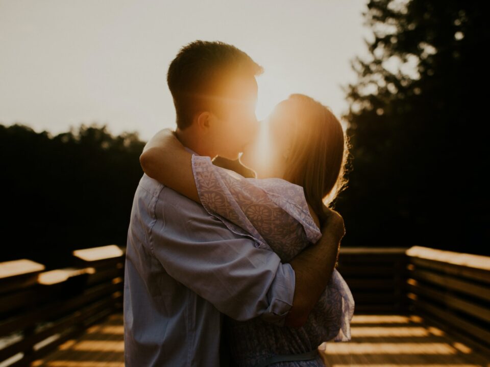 man and woman kissing during sunset