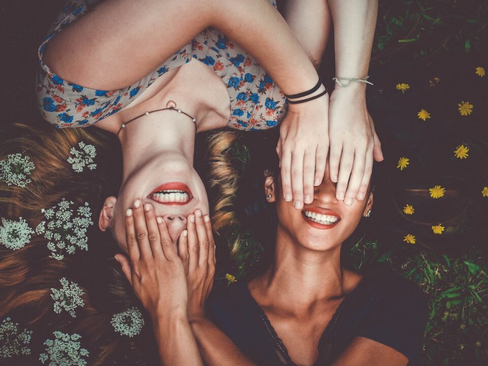 man and woman smiling while laying on lawn field