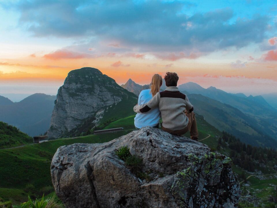 couple sitting on rock facing mountain view
