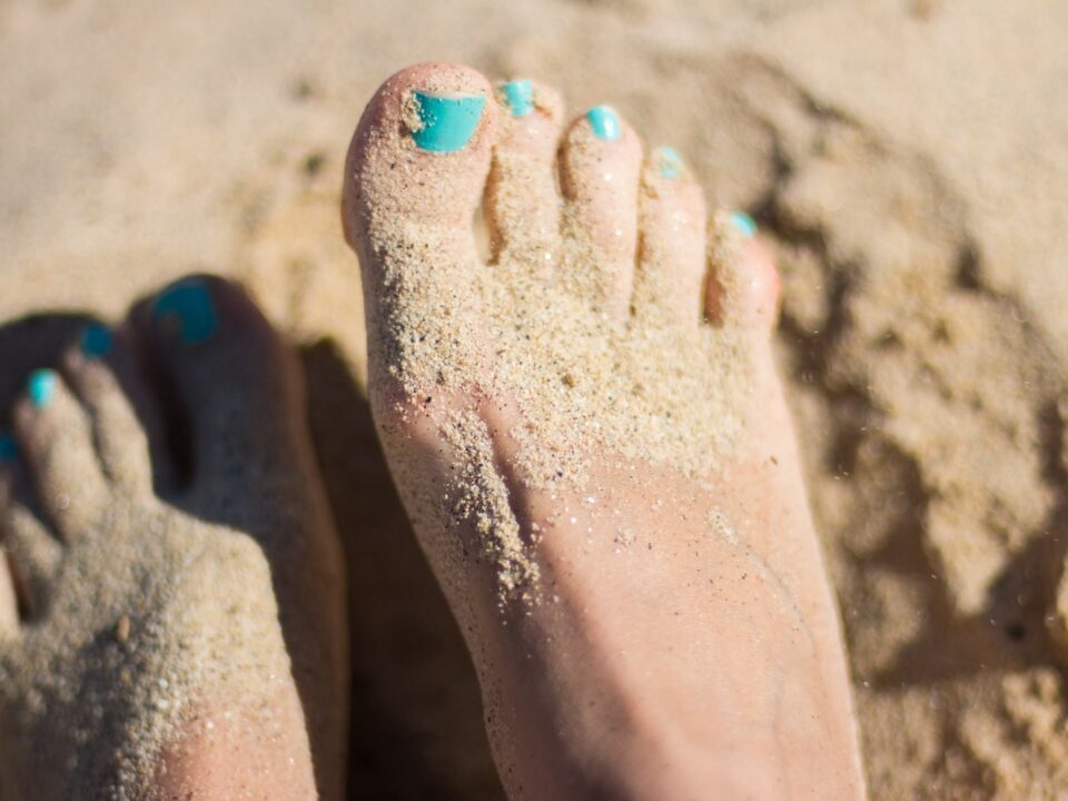 person sky-blue nail polish feet on brown sand