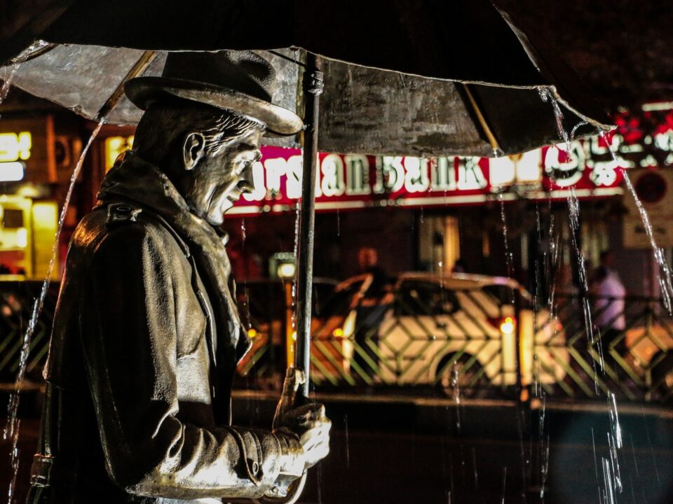 shallow focus photography of man carrying umbrella statue