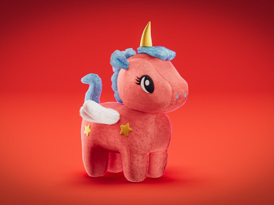 a pink stuffed animal with a gold horn on its head