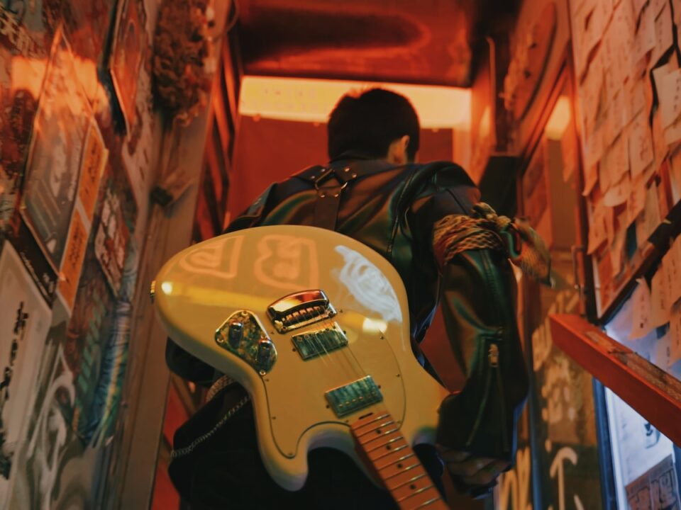 man in black jacket playing white electric guitar