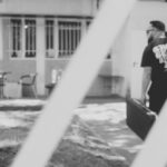 grayscale photography of man carrying case