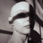 a woman with a shaved head and earrings