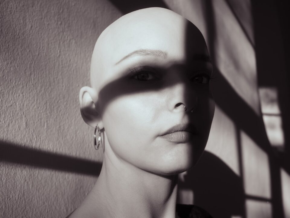 a woman with a shaved head and earrings