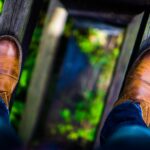man wearing brown leather dress shoes stepping on brown wood