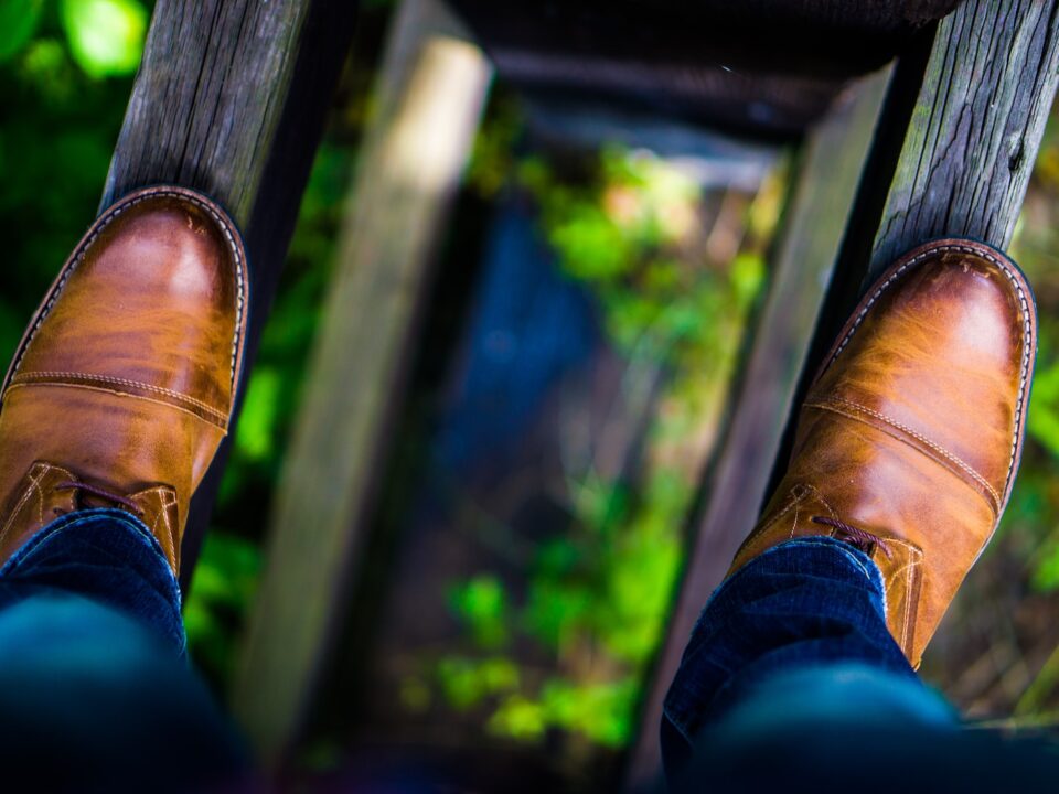 man wearing brown leather dress shoes stepping on brown wood