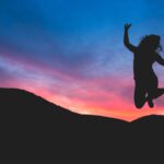 silhouette of person jumping during dawn