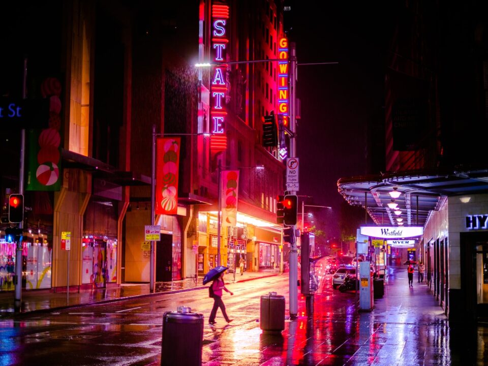 man in black jacket and blue denim jeans walking on street during night time
