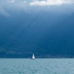 a sailboat in a large body of water with mountains in the background