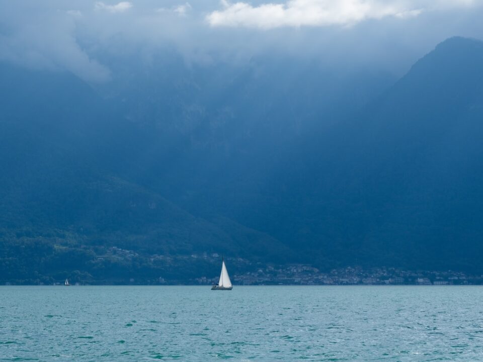 a sailboat in a large body of water with mountains in the background