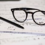 black framed panto-style eyeglasses beside black ballpoint pen