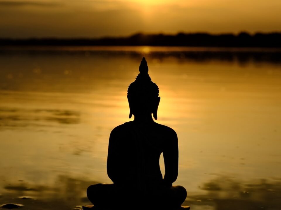 a buddha statue sitting in front of a body of water