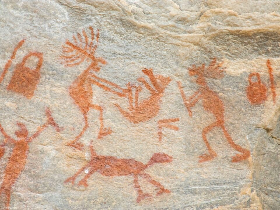 a rock painting of people and animals on it