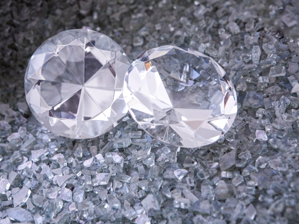two diamonds sitting on top of a pile of crushed glass