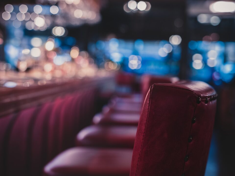 a row of red chairs sitting in front of a bar