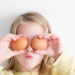 girl holding two eggs while putting it on her eyes