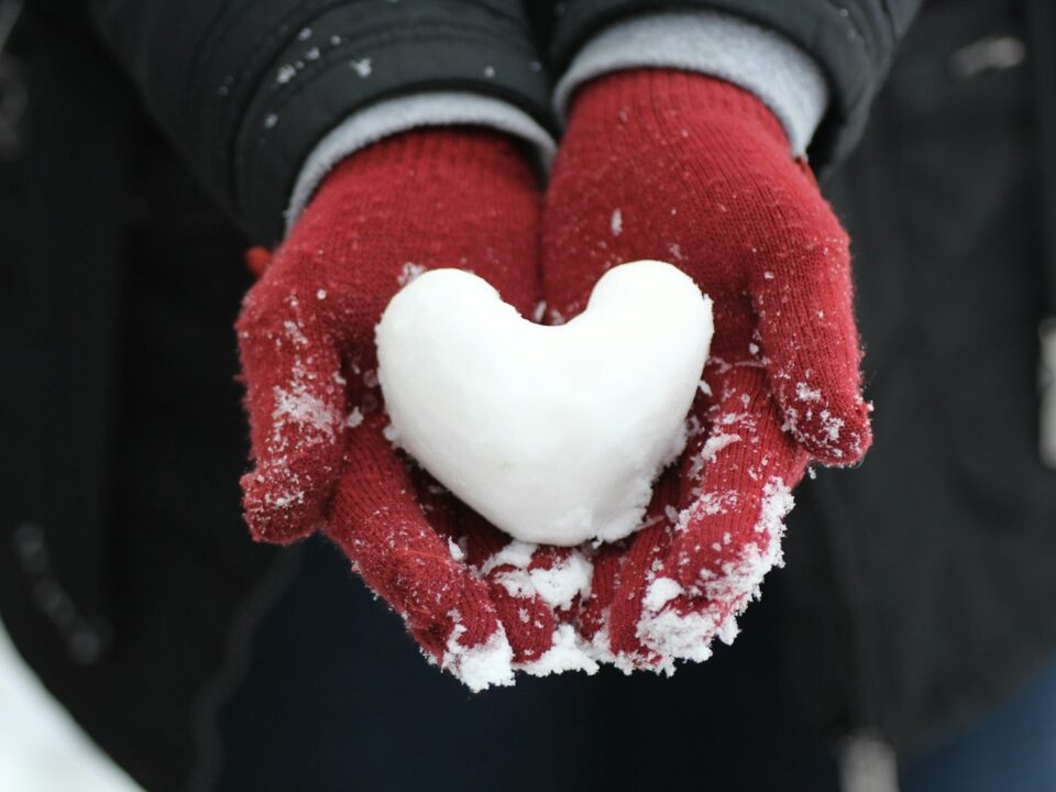 person holding heart-shaped snow