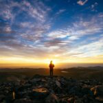person standing on rocky mountain under blue sky during daytime