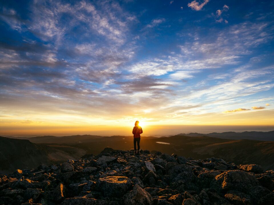 person standing on rocky mountain under blue sky during daytime