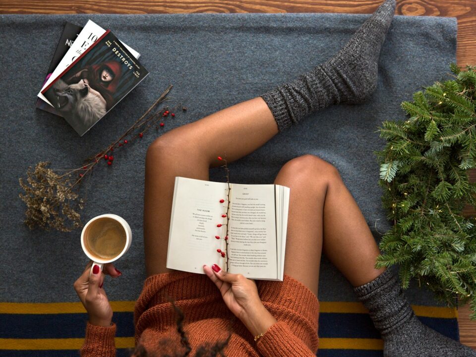 opened book on person's lap with gray socks