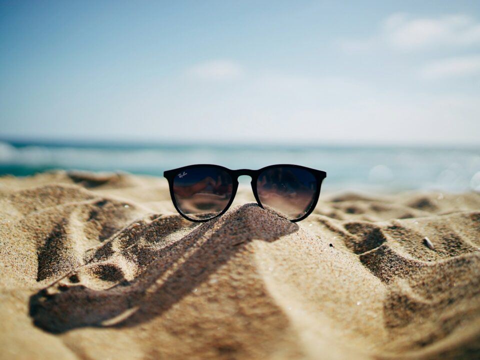 black Ray-Ban Wayfarer sunglasses on beach sand