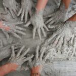 people's hand on gray mud