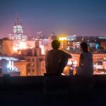 man and woman chilling on rooftop in front of high-rise buildings