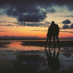 silhouette of two person standing near seashore