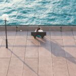 man in black shirt sitting on chair near swimming pool during daytime