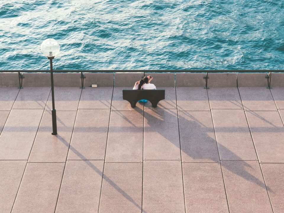 man in black shirt sitting on chair near swimming pool during daytime