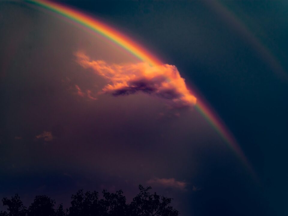 rainbow on blue sky with gray clouds during daytime
