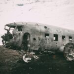 grayscale photo of abandoned airliner in open field