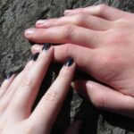 two hands holding each other on a rock