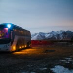 white and black bus running near the mountain