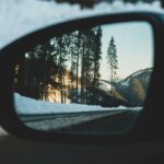 car side mirror showing snow covered trees