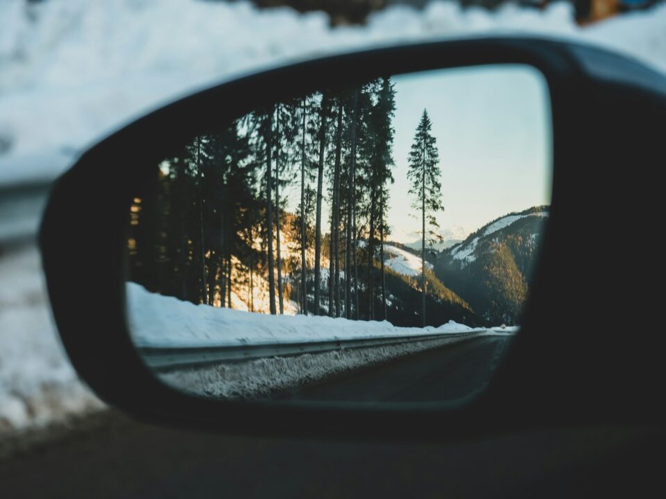 car side mirror showing snow covered trees