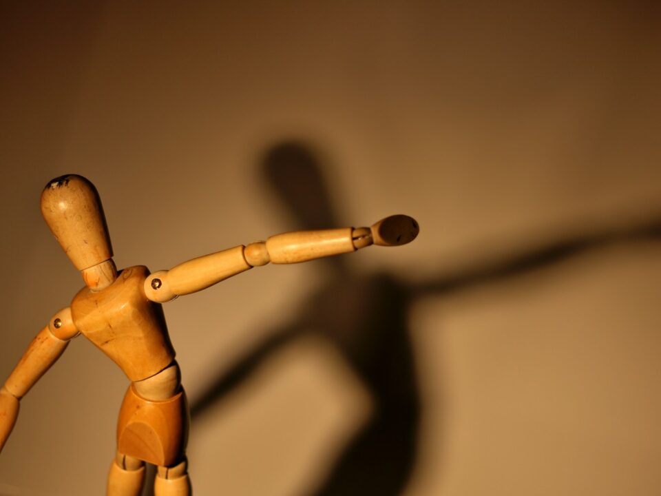 a wooden toy with a long shadow on a wall