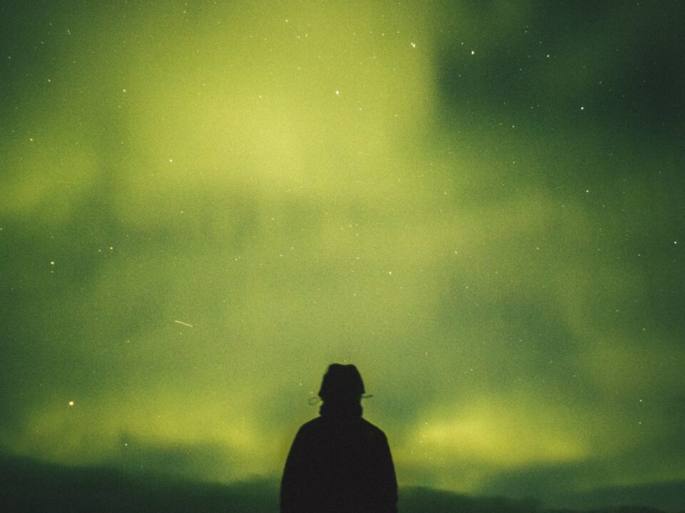 person standing under green aurora borealis