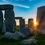 the sun is setting behind the stonehenge monument