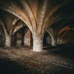 a dimly lit room with brick floors and arches
