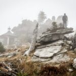 person standing on rock formation with fogs