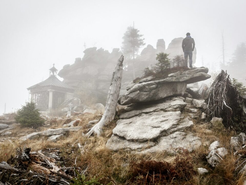 person standing on rock formation with fogs