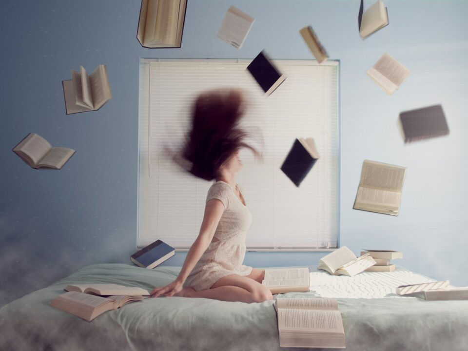 woman sitting on bed with flying books