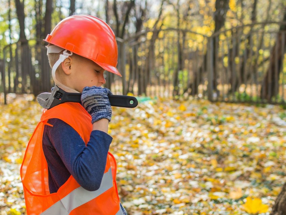 boy in orange and black jacket wearing red helmet holding black dslr camera